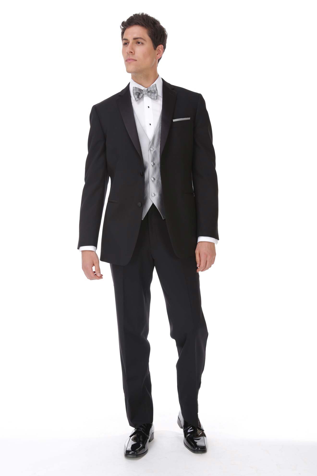 A man in an Allure Charcoal tuxedo is standing in front of a white background, showcasing the elegance of suit rental.