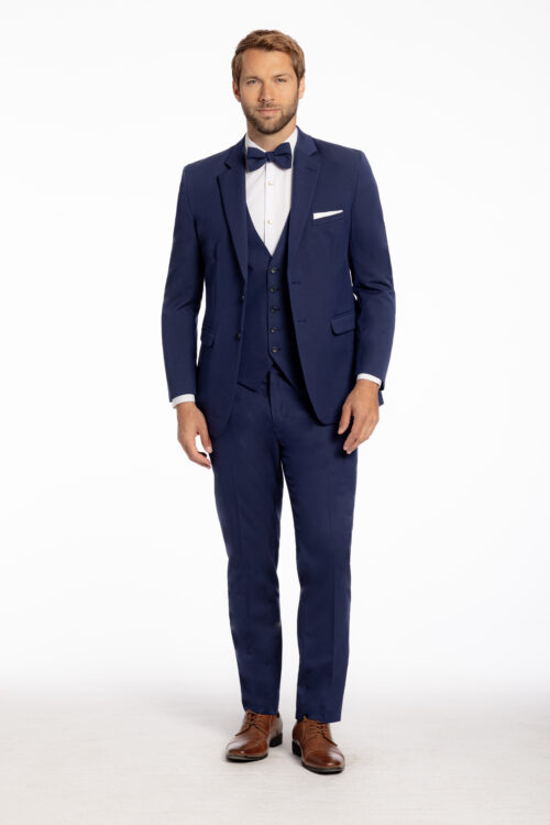 Man in a Rust Metro Slim Fit Suit with a bow tie and brown shoes stands against a plain white background.
