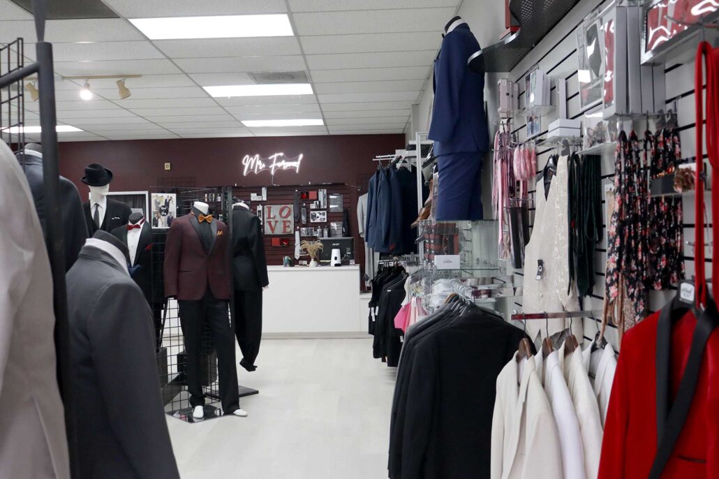 A men's clothing store specializing in suit rental, featuring mannequins showcasing a range of suits.